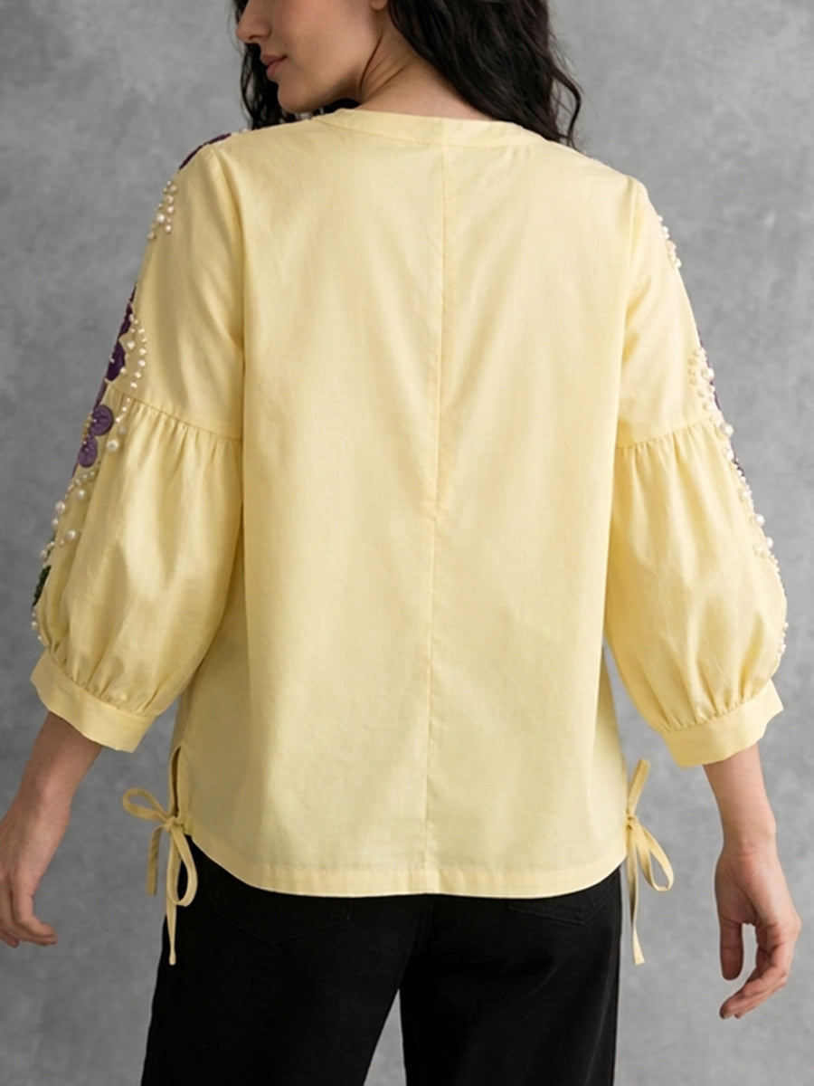 Seitliche Ansicht der gelben Damenbluse mit Puffärmeln und bestickten Details
